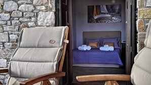 Une pièce confortable avec un lit, deux fauteuils et un mur en pierre.