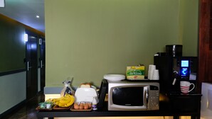 A kitchenette with a microwave, coffee maker, and a tray of food including eggs, bananas, and bread. - Hotel Luna (Jeonju)