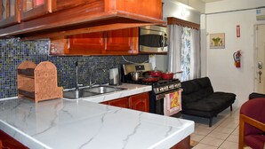 Una cocina con armarios de madera, microondas, estufa y salpicadero de azulejos.