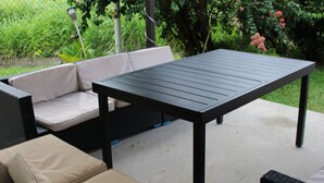 Un espacio al aire libre con un patio, una mesa de metal negro y un sofá beige.