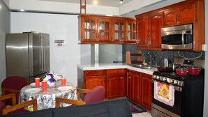 Cocina compacta con armarios de madera, refrigerador de acero inoxidable, microondas y estufa.