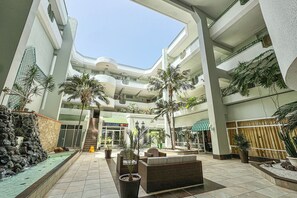 Ein mehrgeschossiges Atrium mit einer zentralen Treppe, Blumentöpfen und Außenbereichen mit Sitzgelegenheiten.