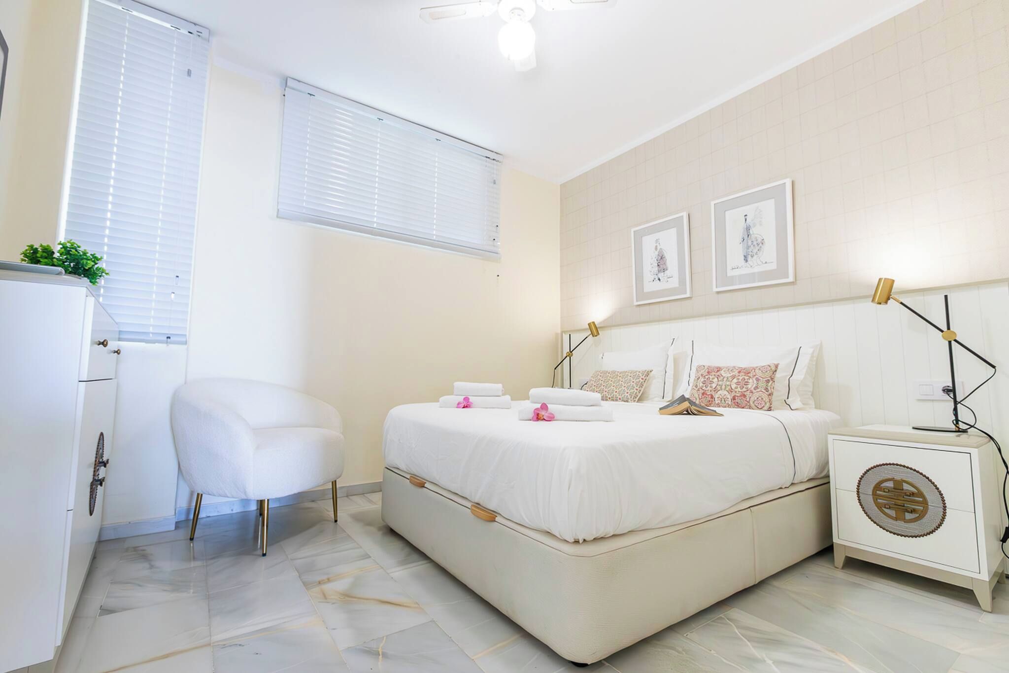 Un dormitorio con cama, mesitas de noche, una silla y un armario.