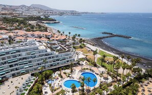 A resort with multiple swimming pools, a beach, and a view of the ocean.