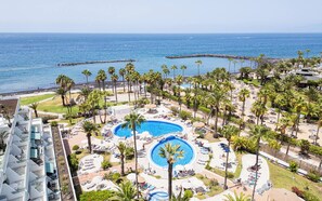 A resort with multiple swimming pools, palm trees, and a view of the ocean.