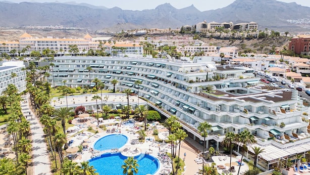Een resort met meerdere zwembaden, een centrale binnenplaats en uitzicht op bergen.