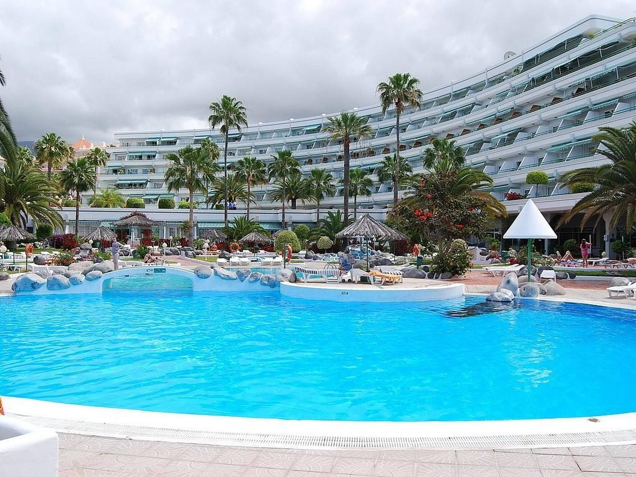 Ein großer Swimmingpool mit einem modernen Hotel im Hintergrund.