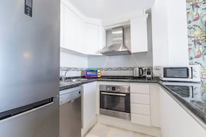 Een kleine keuken met een roestvrijstalen koelkast, een Bosch oven, een magnetron en een broodrooster.