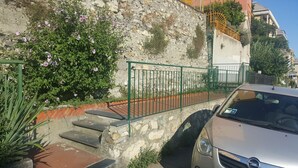 A car parked next to a stone wall with steps leading up to a gate. - Martino apartment (Genova)