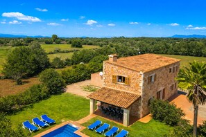 Une villa en pierre dotée d’une piscine, d’un espace salon extérieur et offrant une vue sur la campagne.