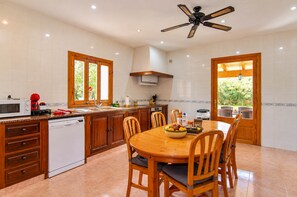 Una cocina con armarios de madera, lavavajillas, microondas y una mesa de comedor con sillas.