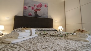 Ein ordentlich bezogenes Bett mit gefalteten Handtüchern und einem Zweig weißer Blumen.
