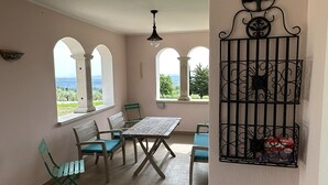 A room with a table and chairs, arched windows, and a decorative metal piece on the wall.
