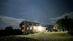 A two-story house with a sloped roof, a front porch, and a well-lit exterior.