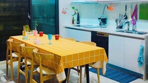 A modern kitchen with a dining table, chairs, and a variety of kitchen utensils and appliances. - Come Home Travel (Tainan)