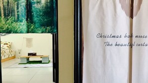 A bedroom with a bed, bedside table, and a large forest mural on the wall. - Come Home Travel (Tainan)