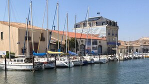 A marina with several boats docked, a building with a tiled roof, and a clear sky.