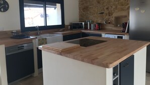 A modern kitchen with a central island, a built-in microwave, and a refrigerator.
