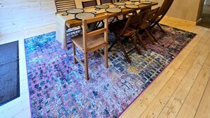 Una stanza con rivestimento in legno, un tavolo da pranzo, sedie e un tappeto colorato.