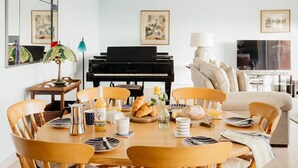Ruokailutilassa on piano, sohva ja taustalla näkyy televisio.