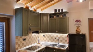 Una cocina con armarios verde oscuro, un refrigerador negro y salpicadero de azulejos.