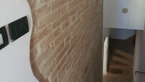 Una escalera con un muro de ladrillo a un lado y un muro blanco al otro.