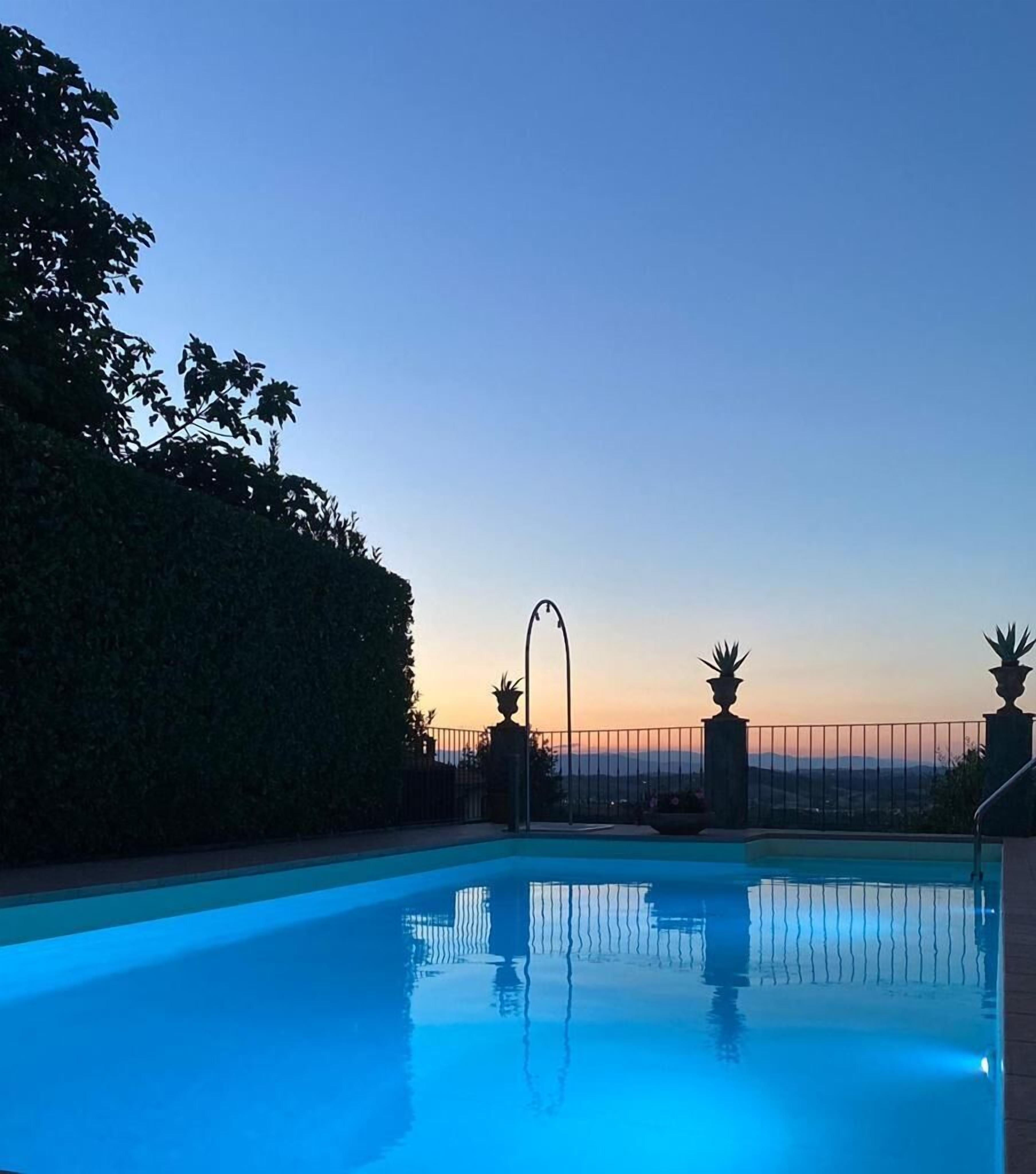 Ein Schwimmbecken mit Blick auf den Sonnenuntergang und Berge im Hintergrund.