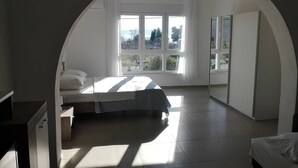 Een slaapkamer met een bed, een bureau en een groot, rondbogig raam.