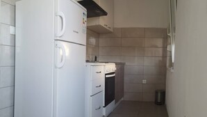 Een keuken met een witte koelkast, een inbouwoven en een vuilnisbak.