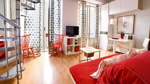 Un salon moderne avec un canapé rouge, un téléviseur, une table à manger et un escalier.