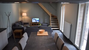 Un salon moderne avec un canapé, une table à manger et un téléviseur.