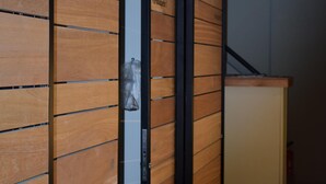 Un couloir aux murs lambrés et une porte donnant sur une pièce.