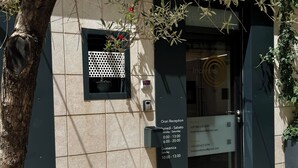 A building entrance with a reception desk, a small window with a decorative screen, and a door with a sign indicating reception hours. - Incentro Rooms (Polignano a Mare)