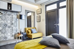 A modern hotel room with a bed, a yellow armchair, a small side table, and a patterned wallpaper. - Incentro Rooms (Polignano a Mare)