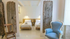 Une chambre d’hôtel avec deux lits, une chaise en bois et un fauteuil bleu.