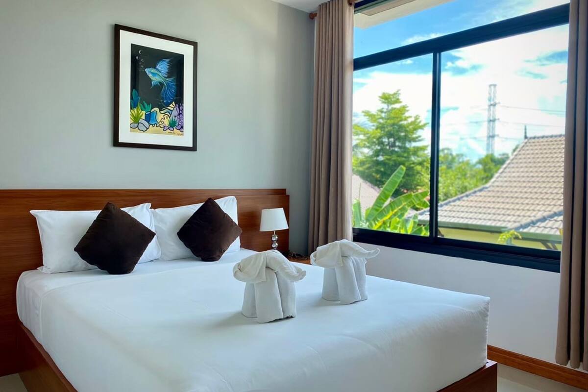 Habitación de hotel con una cama grande, un cuadro en la pared y vistas a zonas verdes.
