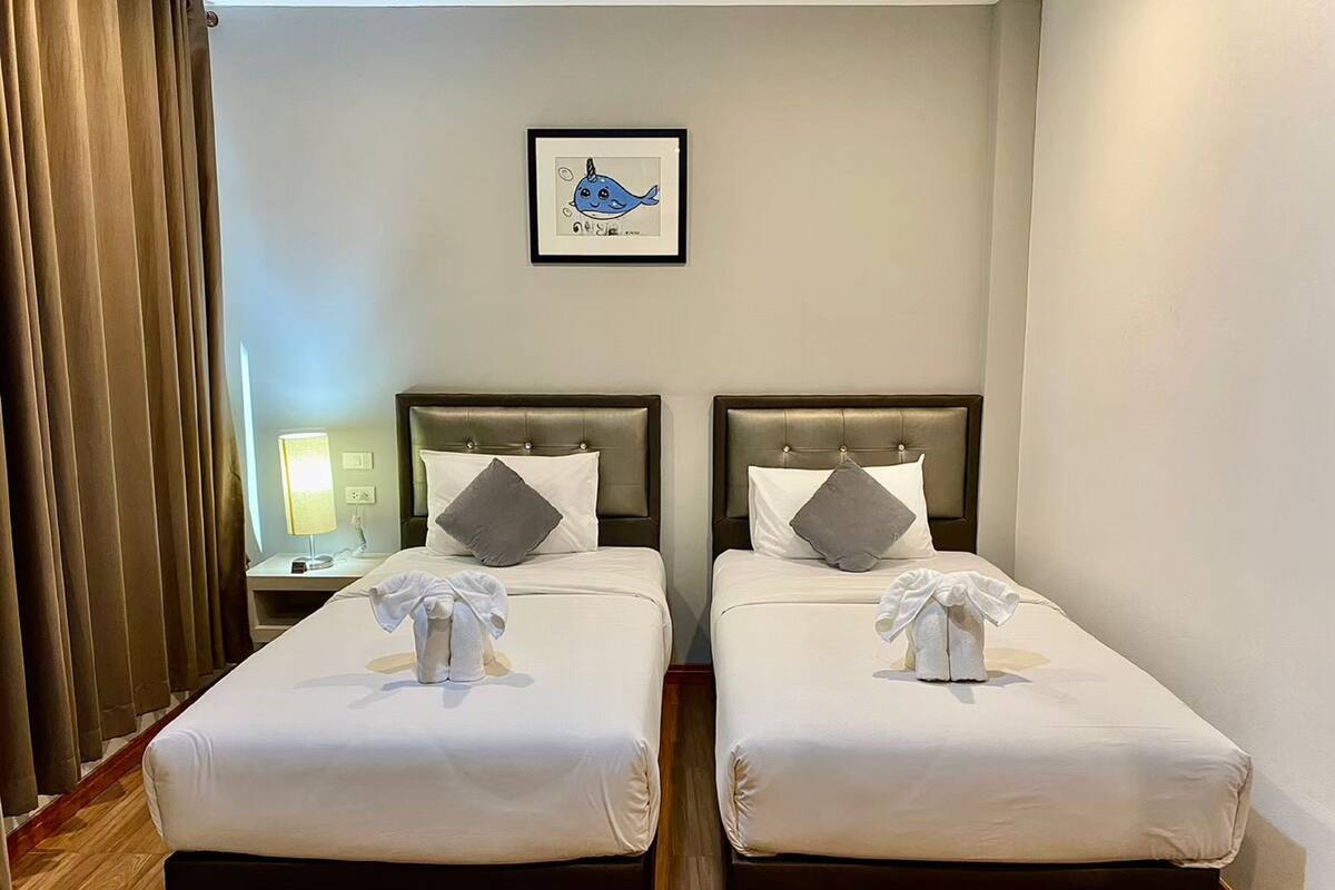 Una habitación de hotel con dos camas, cada una con cabecera, almohadas y toallas.