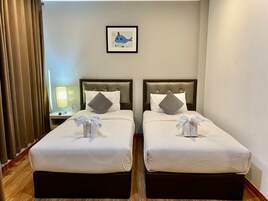 Una habitación de hotel con dos camas, cada una con cabecera, almohadas y toallas.