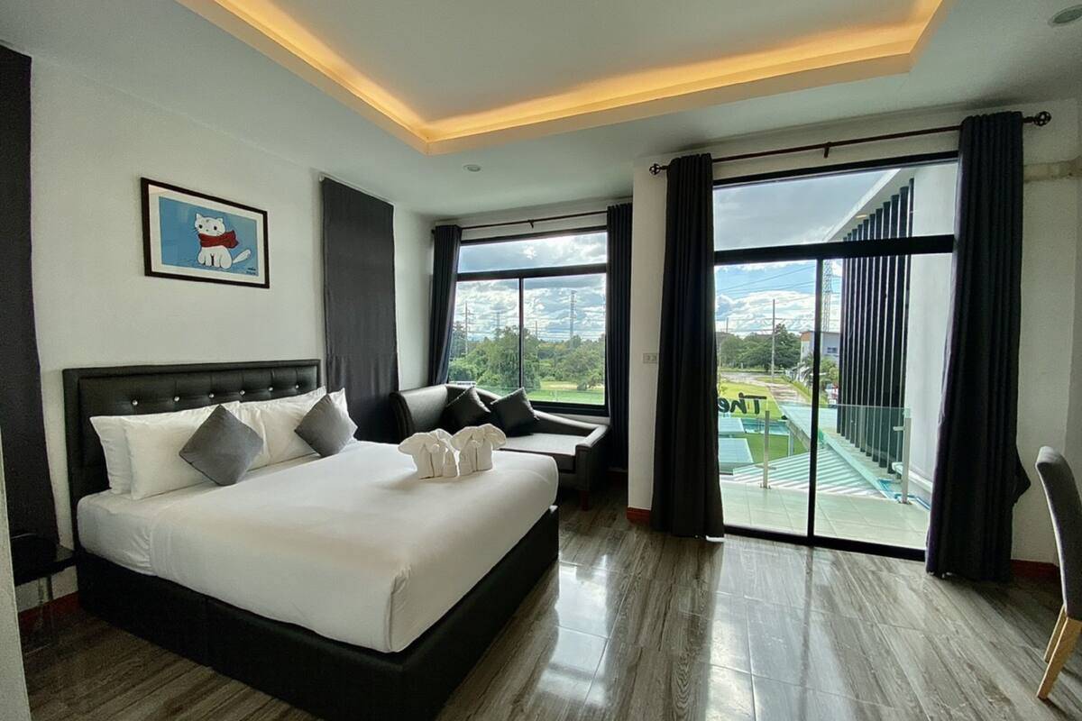 Habitación de hotel moderna con una cama grande, zona de estar y balcón con vista a la ciudad.