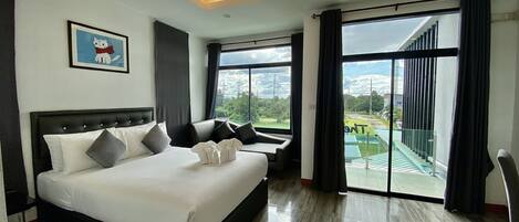 A modern hotel room with a large bed, a seating area, and a balcony with a view of the city.