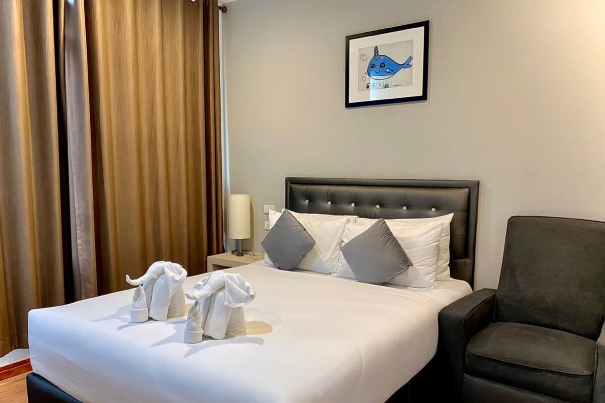 Una habitación de hotel con una cama bien hecha, un cuadro de una ballena en la pared y una silla junto a la cama.