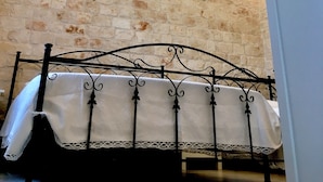 A room with exposed brick walls, a wrought iron bed frame, and a hanging light fixture. - Villa Valentina - Authentic Stone House in the heart of Puglia (Cisternino)