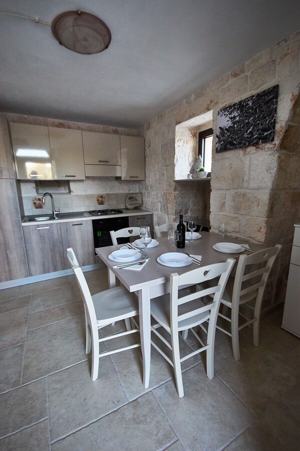 Una cocina compacta con comedor. Tiene un lavamanos, estufa y armarios.