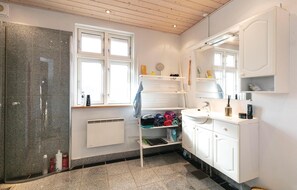 Enjoy grooming in the spacious bathroom with a large mirror, heater, and glass door shower.
