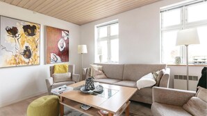 Una sala de estar moderna con un sofá, sillones, una mesita de centro y obras de arte en las paredes.
