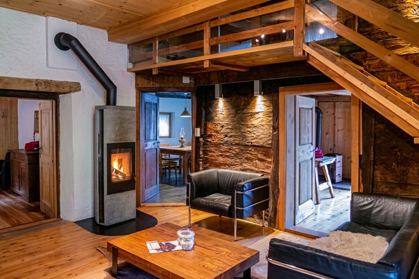 A cozy interior with a fireplace, wooden furniture, and a stone wall.
