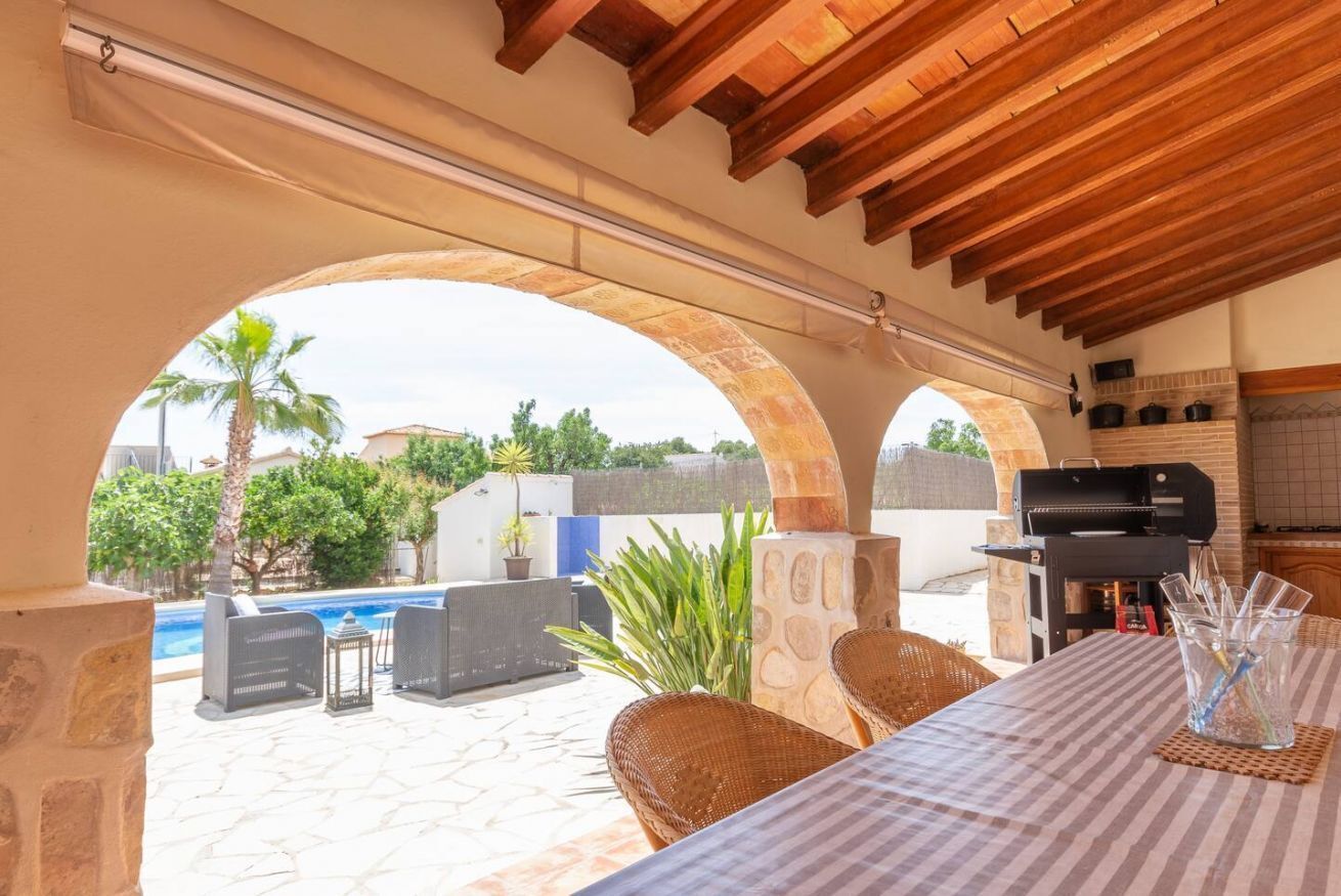 Eine Terrassenanlage im Freien mit Pool, Grill und Korbmöbeln.
