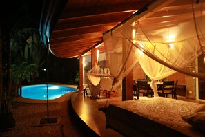 A bedroom with a bed, a mosquito net, a small pool, and a dining area with chairs and a table. - Private Jungle villa Casa Drop In with private saltwater pool, walk to the beach (CobanSanta Teresa de Cobanoo, Puntarenas)