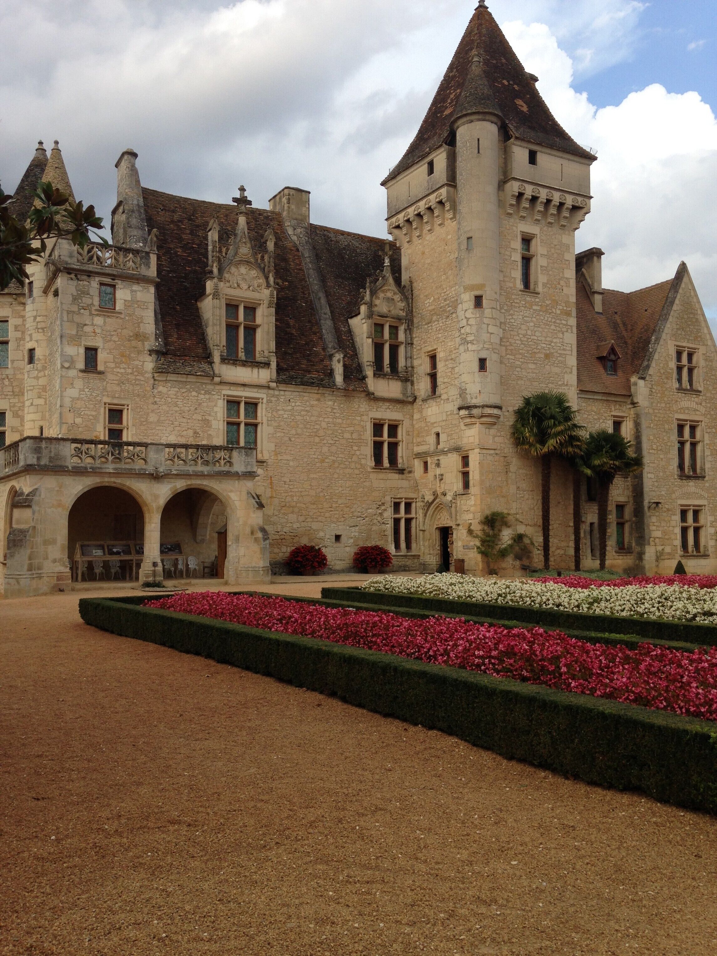 Un bâtiment historique en pierre, doté d’une tour centrale, d’une entrée en arc de cercle et d’une façade symétrique.