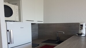 Eine kleine Küche mit Kühlschrank, Mikrowelle und Kaffeemaschine.